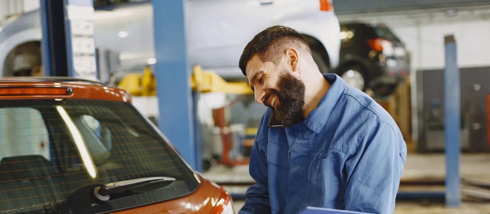 Mechanic in coveralls checking paperwork at a car service